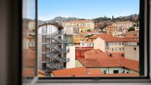 A view of a cityscape through a window, featuring a mix of modern and traditional buildings, a prominent staircase, and a clear sky.