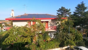 Ein Gebäude mit rotem Dach, Solaranlage und Satellitenschüssel.
