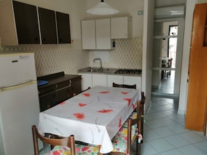 Une cuisine équipée d’une table à manger, de chaises, d’un réfrigérateur, de placards et d’un évier.