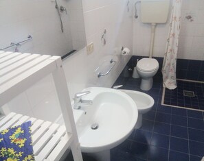 Un baño con lavamanos blanco, un bidé, un inodoro y una zona de ducha.