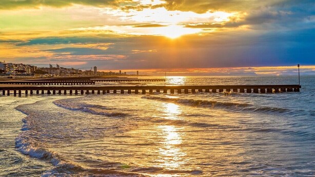 A pier extending into the water with a sunset in the background.