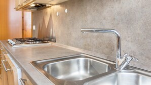 Une cuisine équipée d’éviers en acier inoxydable, d’une cuisinière à gaz et d’armoires en bois.