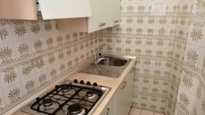 A kitchen with a gas stove, a sink, and patterned tiles. - Apartment 'Residence Torino 85' with Shared Pool and Private Terrace (Jesolo)