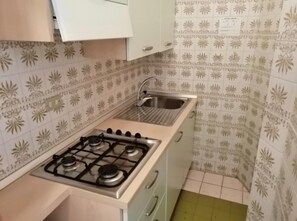 Een koelkast, een kookplaat, kookgerei, borden en bestek