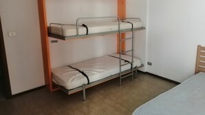 A bunk bed with three levels, a wooden chair, and a table with a white tablecloth. - Apartment 'Residence Torino 85' with Shared Pool and Private Terrace (Jesolo)