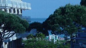 A coastal building with balconies overlooking the sea, surrounded by greenery and parked cars. - Apartment 'Residence Torino 85' with Shared Pool and Private Terrace (Jesolo)
