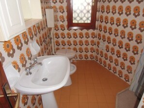 Ein Badezimmer mit Waschbecken, Toilette und Wandverkleidung mit Muster.