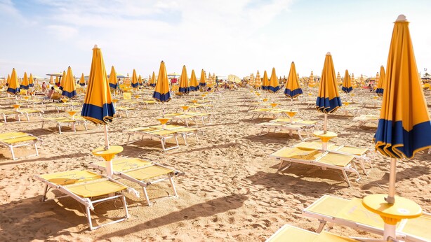 Ein Strand mit Liegestühlen und Sonnenschirmen.