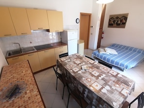 A compact kitchen with a sink, cabinets, and a dining area with a table. - Euroholiday Village 2G, Wi-Fi and Air Conditioning (Jesolo)