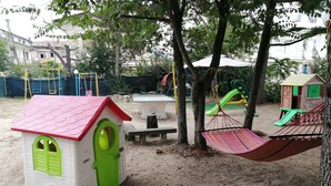 A playground with a small house, swings, and slides. - Euroholiday Village 2G, Wi-Fi and Air Conditioning (Jesolo)