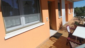 A balcony with a table and chairs, a window with blinds, and a door leading to another room. - Euroholiday Village 2G, Wi-Fi and Air Conditioning (Jesolo)