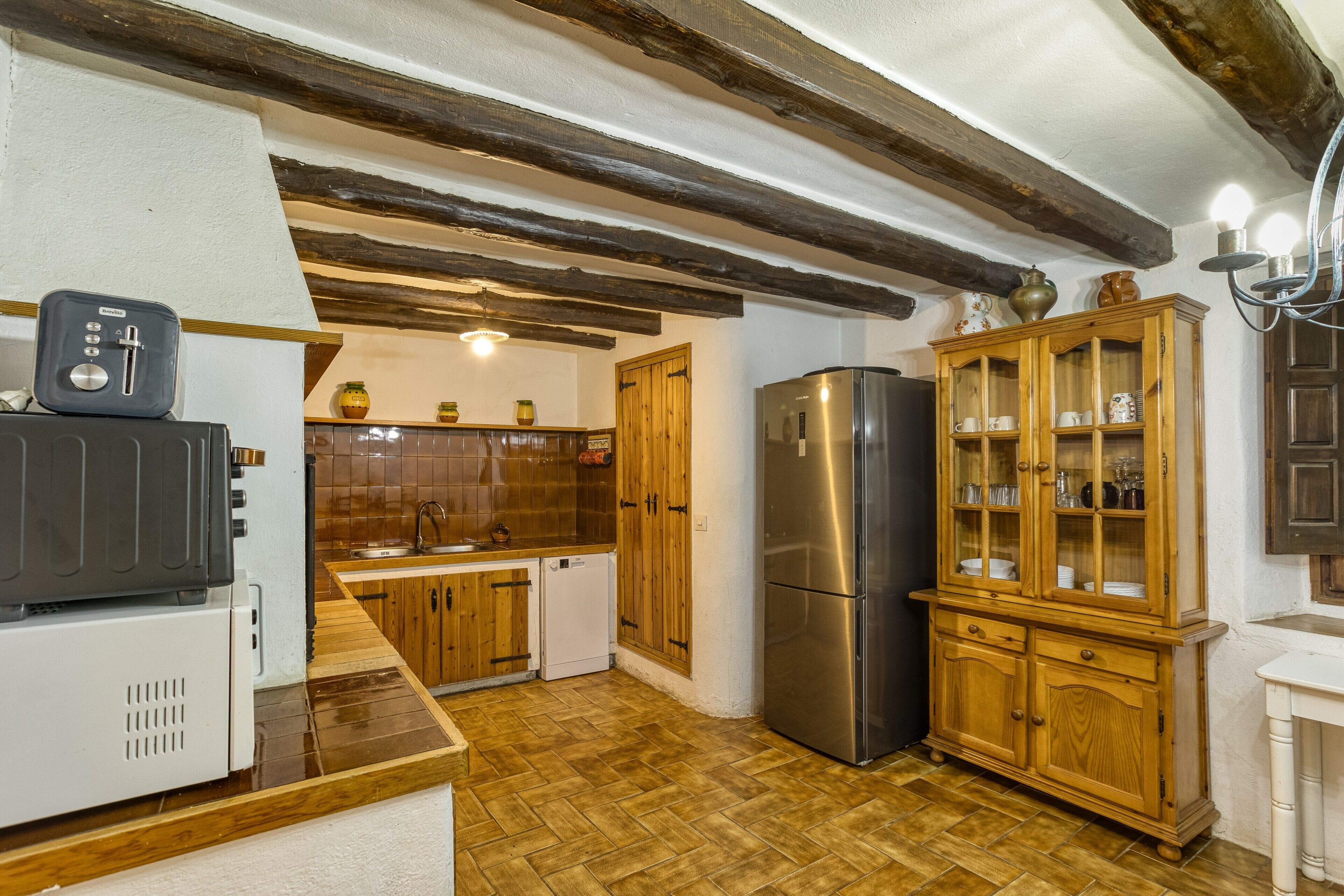 Eine Küche mit Holzausstattung, einem Edelstahlkühlschrank, einem Toaster und einem Schrank mit Glastüren.
