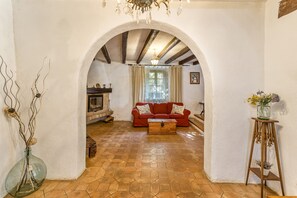 A living room with a red sofa, a wooden coffee table, a fireplace, and a tiled floor.