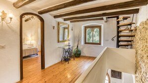 A room with wooden floors, a staircase, a mirror, and a table with a vase. - Chalet 'El Revolt De Martís' with Private Pool, Private Terrace and Wi-Fi (Martís)