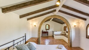 A bedroom with a bed, a nightstand, a dresser, and an arched doorway leading to a bathroom. - Chalet 'El Revolt De Martís' with Private Pool, Private Terrace and Wi-Fi (Martís)