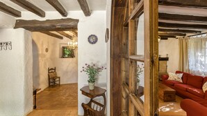 A rustic interior with exposed wooden beams, a red sofa, a wooden table with a vase, and a chair. - Chalet 'El Revolt De Martís' with Private Pool, Private Terrace and Wi-Fi (Martís)