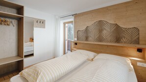 A bedroom with a bed, wooden headboard, built-in wardrobe, and a window.