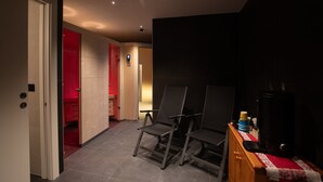 A hotel room with a wooden cabinet, a red door, and a seating area with chairs.