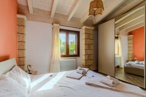 Une chambre à coucher avec un lit, une table de chevet, une lampe, une fenêtre avec des rideaux et un miroir.
