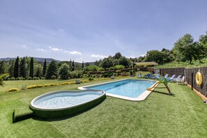 A backyard with a swimming pool, a hot tub, and a slide.
