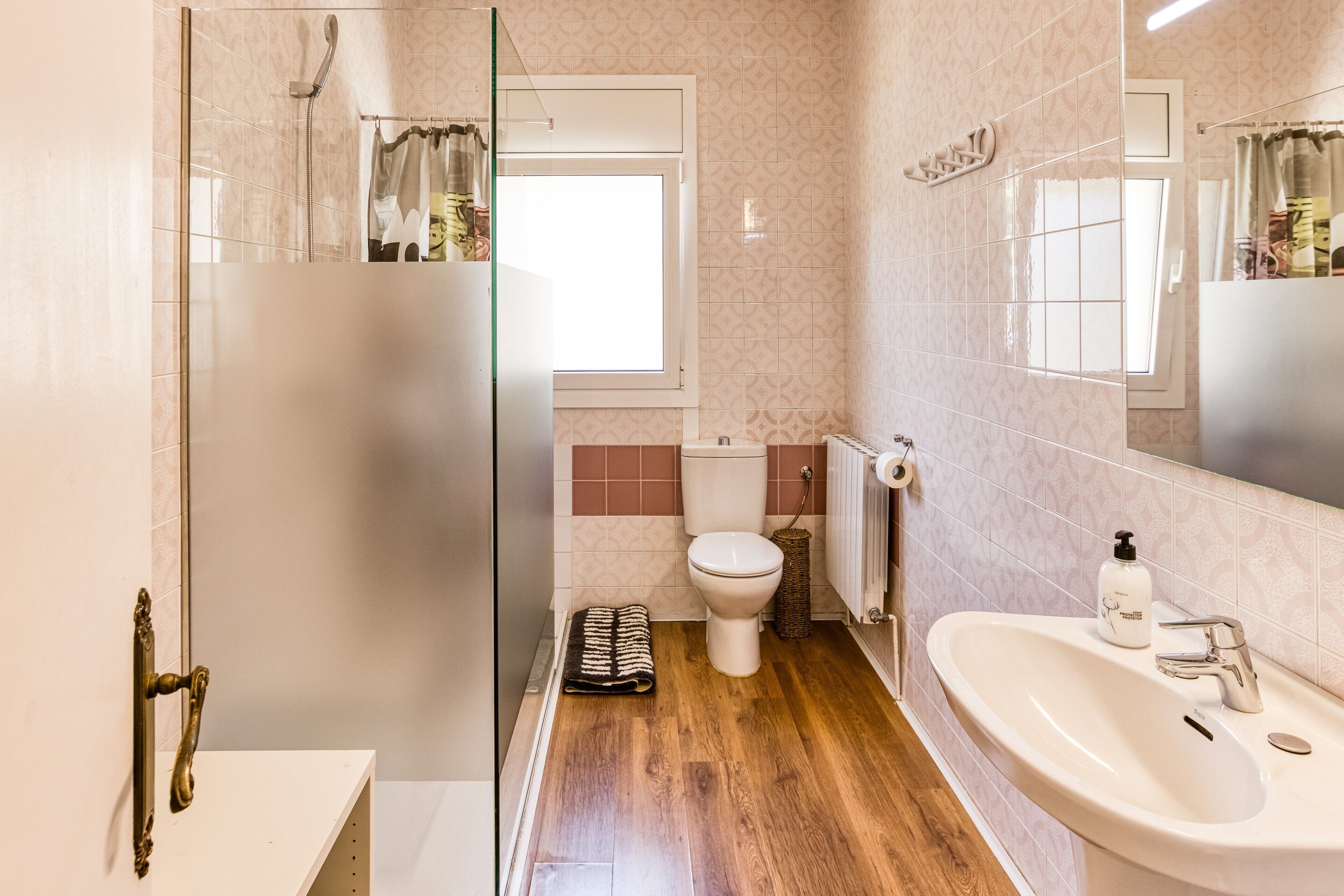 Une salle de bain avec une douche à parois de verre, des toilettes, un lavabo et une fenêtre.