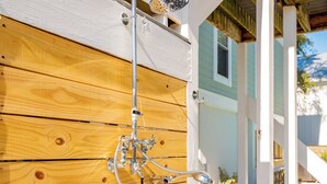 Une terrasse en bois avec une pomme de douche en métal fixée au mur.