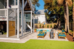 Un patio trasero con piscina, mobiliario exterior y terraza de madera.
