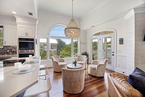 A spacious kitchen with modern appliances, a dining area with round tables, and a seating area with sofas and chairs. - IDEAL IOP Beach Home, 6 BR, Private Pool, Close to Beach, Spacious! (Isle Of Palms)