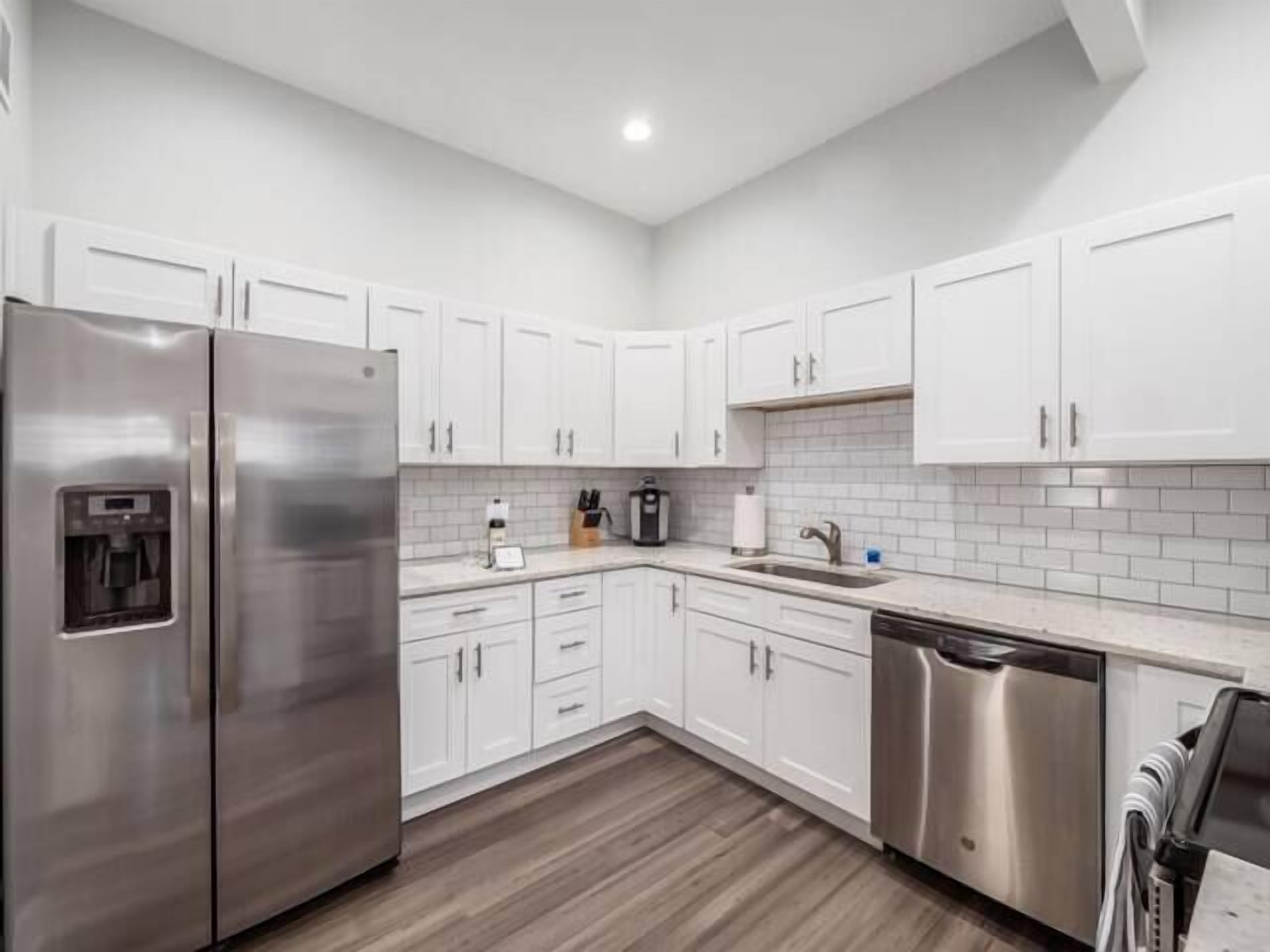 A modern kitchen with white cabinets, stainless steel appliances, and a tiled backsplash.