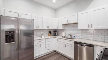 A modern kitchen with white cabinets, stainless steel appliances, and a tiled backsplash.