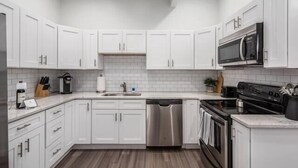 A modern kitchen with white cabinets, stainless steel appliances, and a wooden floor. - Gorgeous Getaway -1BR- Columbus! (Columbus)