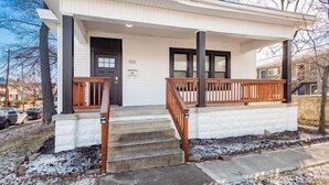 A two-story house with a front porch, a black front door, and a staircase leading to the entrance. - Gorgeous Getaway -1BR- Columbus! (Columbus)