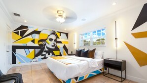 Un dormitorio moderno con una cama de diseño geométrico, una mesita de noche y un amplio mural abstracto en la pared.