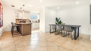 Una cocina moderna con una isla central, taburetes de bar y una mesa de comedor con sillas.