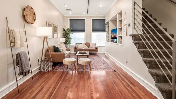 A spacious living room with hardwood flooring, a staircase, and a large window. - THE SKYSCRAPER IN HEART OF COLUMBUS (Columbus)