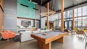 A modern indoor space with a pool table, seating area, and large windows. - Shades of Blue Elegant Suite l Free Parking + Gym (Columbus)