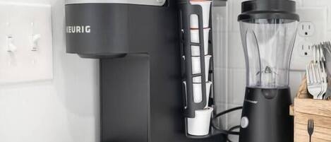 Eine Kaffeemaschine mit integriertem Mahlwerk und ein Mixer auf einer Küchenarbeitsplatte.
