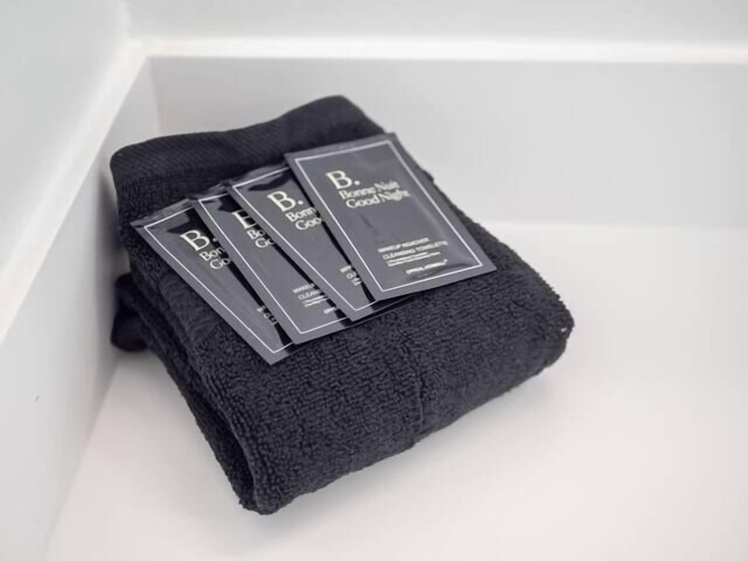 A black towel and three black packages with white text on a white surface.