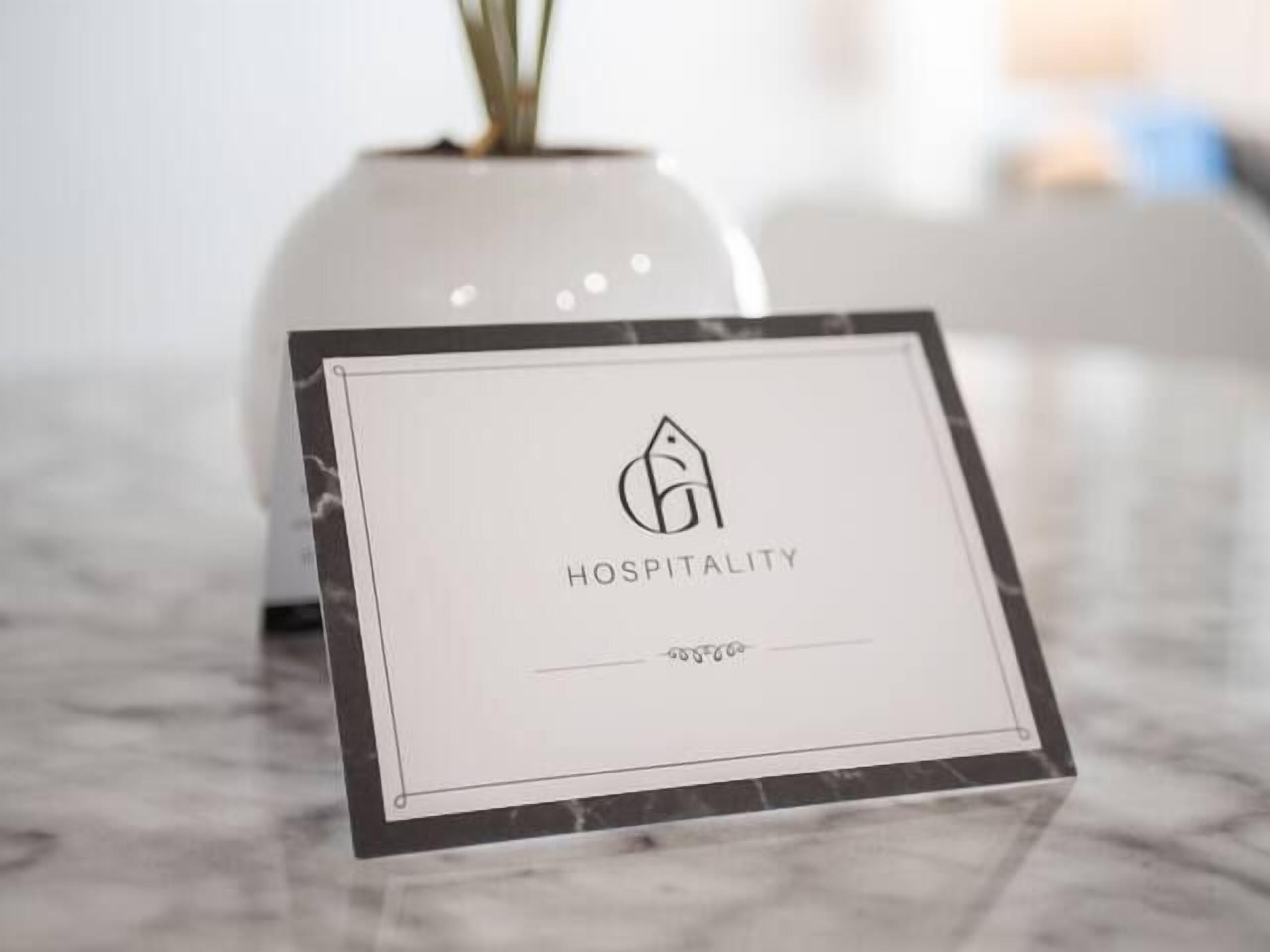 A framed sign with a logo and the word 'HOSPITALITY' on a marble surface.