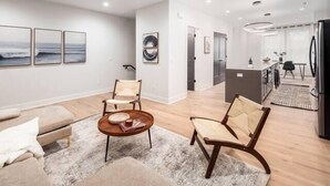A modern living room with a sofa, two armchairs, a coffee table, and artwork on the walls. - Oak Street Rooftop - Columbus! (Columbus)