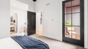 A bedroom with a bed, a ceiling fan, a door leading to a balcony, and a view of the outdoors. - Oak Street Rooftop - Columbus! (Columbus)