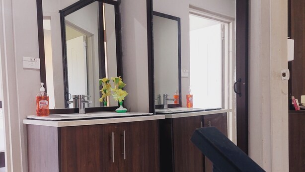 A modern bathroom with a double vanity, large mirrors, and a wooden cabinet.