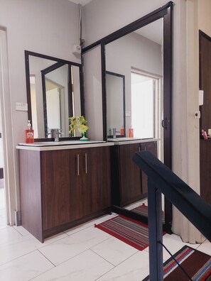 A modern bathroom with a double vanity, large mirrors, and a wooden cabinet.
