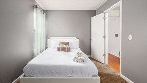 A neatly made bed with white linens and a few decorative pillows, a white headboard, and a small bedside table with a rolled towel. - DUBLIN GETAWAY - NEAR COLUMBUS! (Dublin)