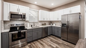 A modern kitchen with white cabinets, stainless steel appliances, and a wooden floor. - Perfect Stay - 2 Bedrooms - Columbus! (Columbus)