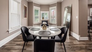 A dining room with a round table, black chairs, and a vase of flowers. - Perfect Stay - 2 Bedrooms - Columbus! (Columbus)