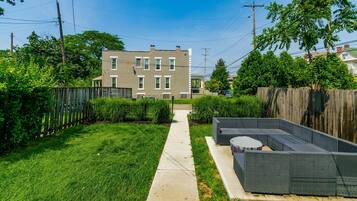 A residential backyard with a paved pathway leading to a seating area with a round table.