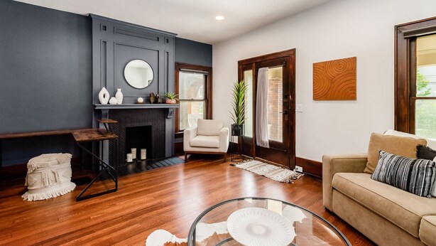 Una sala moderna con chimenea, un espejo redondo, un sofá y una mesa de centro de vidrio.