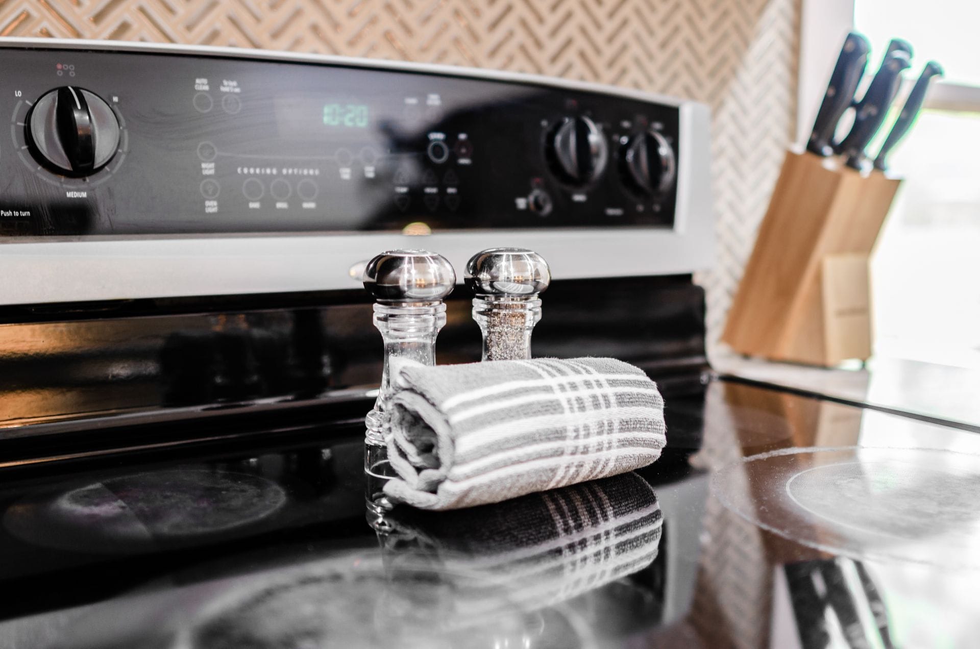 A kitchen with a stove, two salt shakers, and a striped cloth.