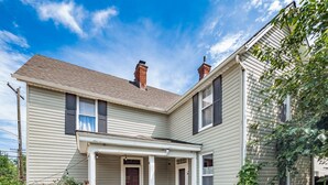 A two-story house with a covered porch and a garden in front.